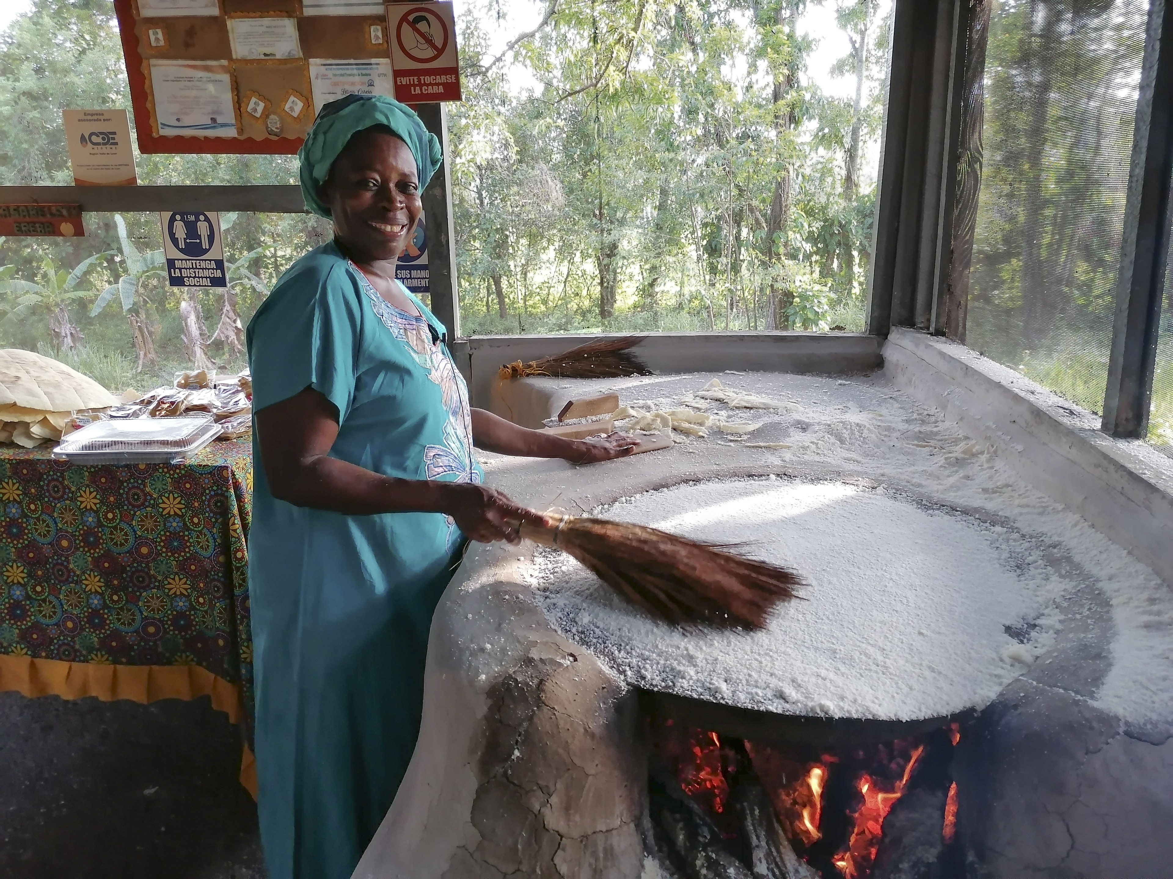Garifuna woman preparing Casabe (cassava bread) on a traditional clay griddle, Honduras
