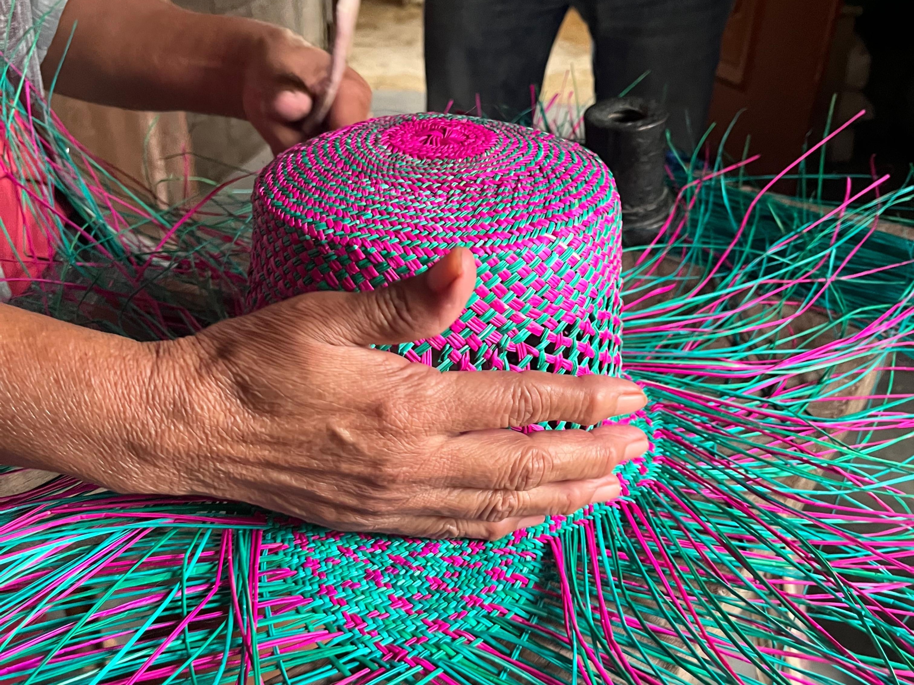 Artisan weaving a traditional junco palm hat